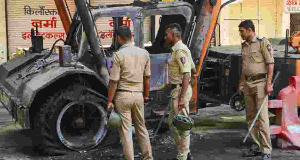 Nagpur: Police personnel near charred remains of a vehicle, a day after violence broke out following an agitation by a right-wing group demanding removal of Aurangzeb's tomb, in Nagpur.
