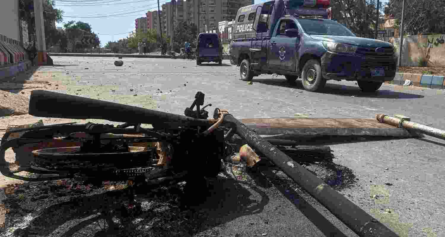 A police vehicle drives past a burnt motorcycle set on fire by angry protestors outside the U.S. Consulate in Karachi, Pakistan, on Sunday.