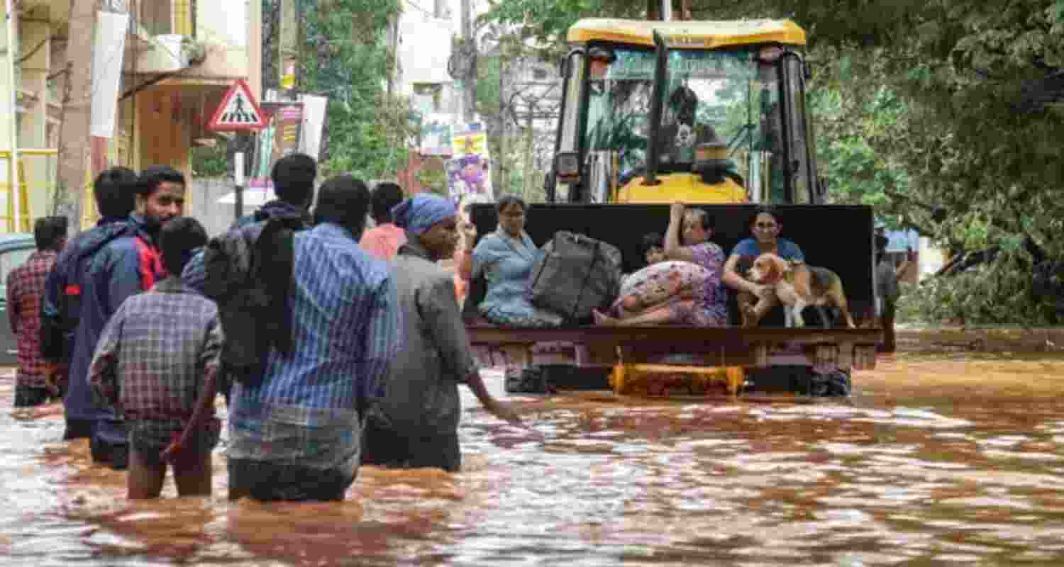 People move through a flooded street after heavy rainfall in Puducherry on December 1, following the landfall of cyclone Fengal.