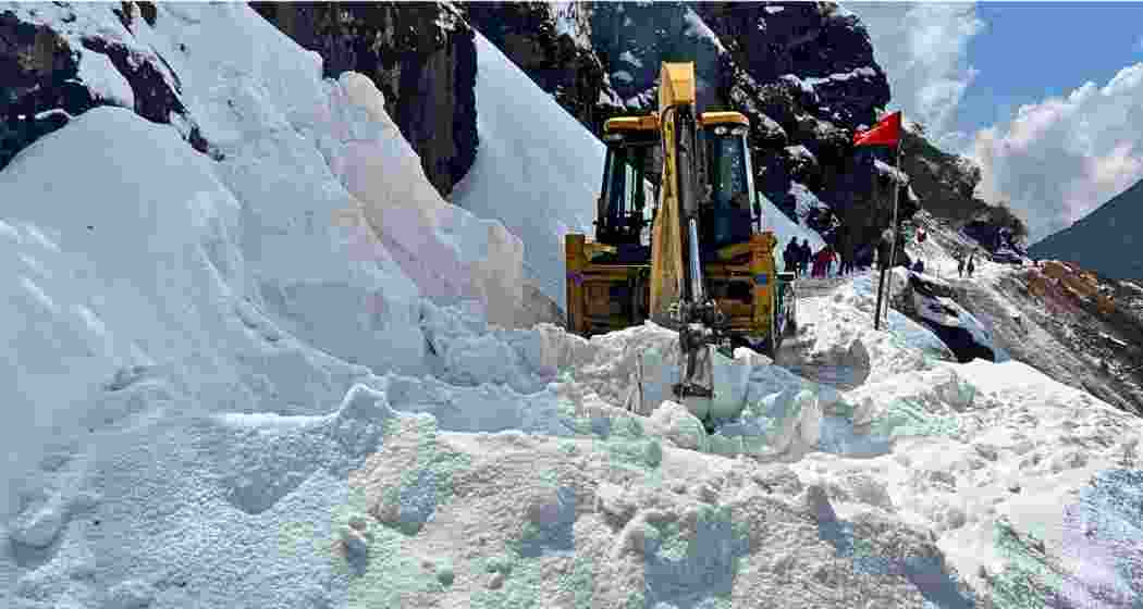 A backhoe loader clears snow from the Tsomgu-Thegu road in East Sikkim, following sudden snowfall that stranded over 200 vehicles.