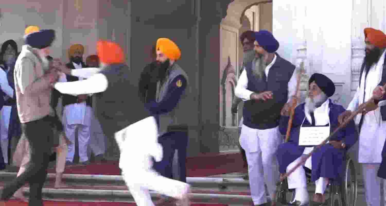 People catch a man who allegedly opened fire at Shiromani Akali Dal leader Sukhbir Singh Badal while the latter was performing the duty of 'sewadar' outside the Golden Temple, in Amritsar, Wednesday. 
