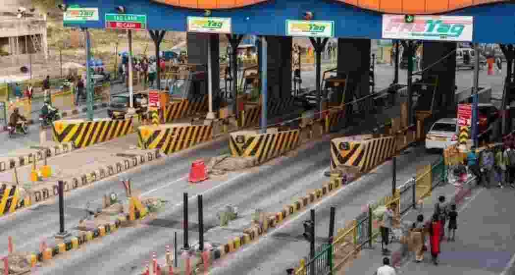 Vehicles pass through a busy National Highway toll plaza. 