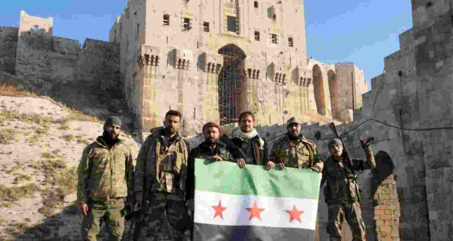 Anti-government fighters hold the Syrian opposition flag at the entrance to Aleppo’s citadel. Image: X