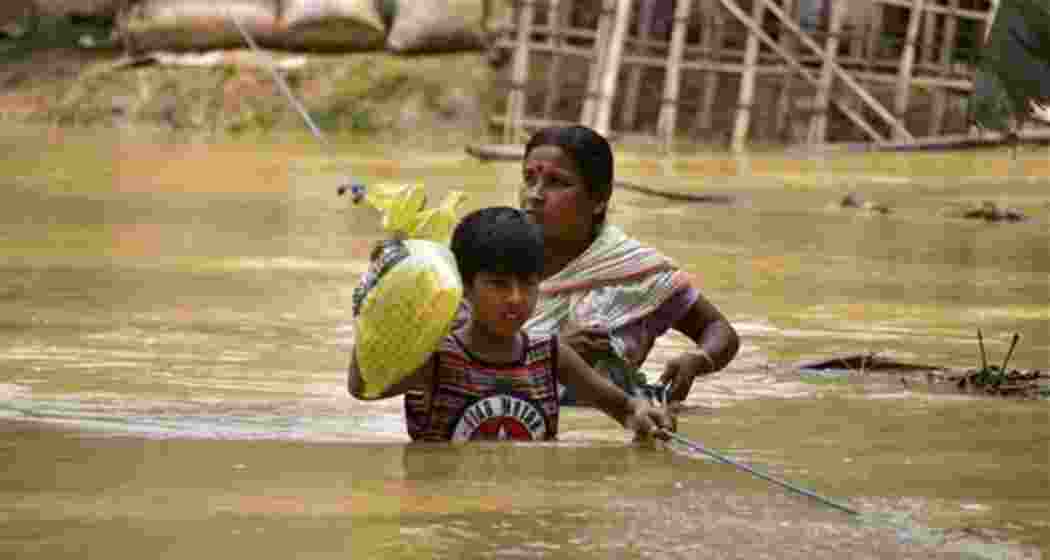 A woman and her child try to walk through a flooded road following rains after the landfall of cyclone Remal, in Nagaon district of Assam on Saturday, June 1, 2024. A woman and her child try to walk through a flooded road following rains after the landfall of cyclone Remal, in Nagaon district of Assam on Saturday, June 1, 2024.
