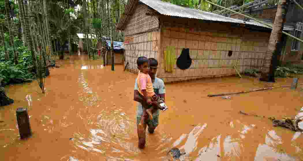 A man carries a child in a flooded village after heavy rains following the landfall of Cyclone Remal at Singi Mari near Kampur in Nagaon district of Assam. A man carries a child in a flooded village after heavy rains following the landfall of Cyclone Remal at Singi Mari near Kampur in Nagaon district of Assam.