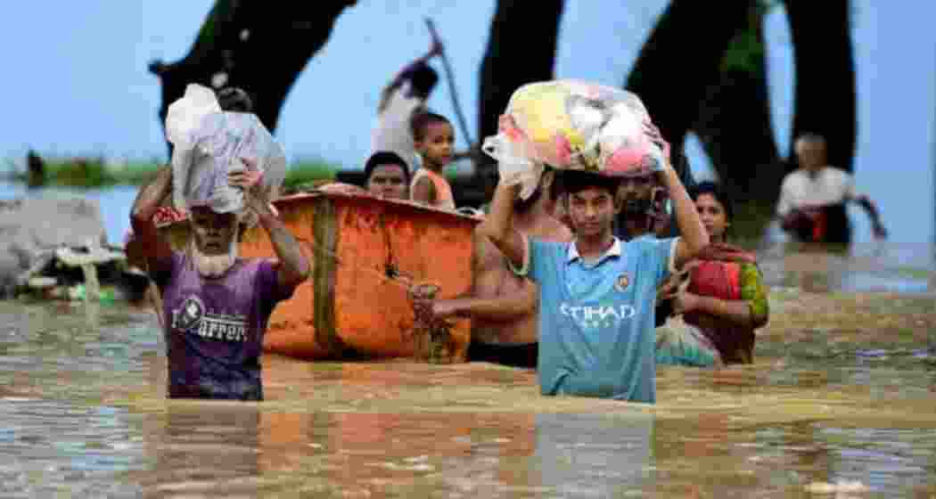 People wade through a flooded area in Bangladesh, navigating the rising waters caused by monsoon rains. People wade through a flooded area in Bangladesh, navigating the rising waters caused by monsoon rains.