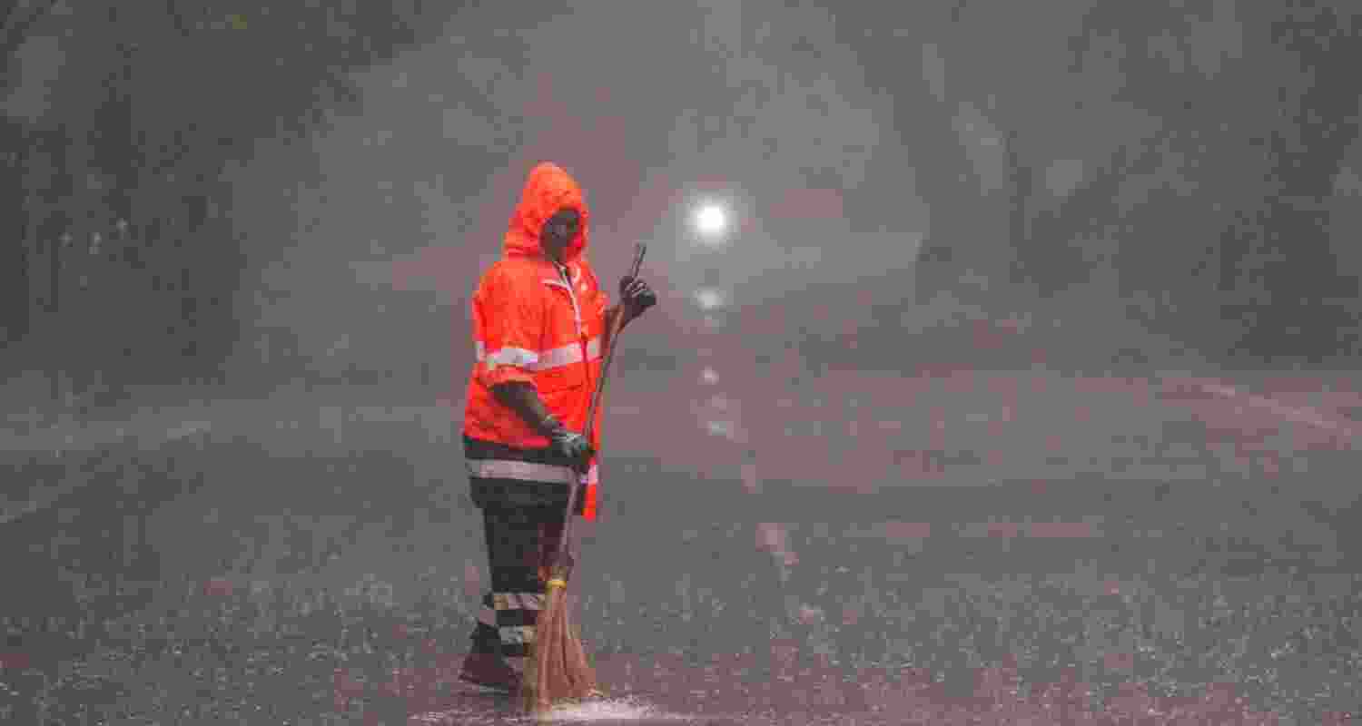 A sanitation worker cleans a street in Chennai while torrential rains fall across the state, on Thursday. A sanitation worker cleans a street in Chennai while torrential rains fall across the state, on Thursday.