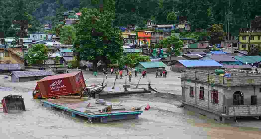 A vehicle that got washed away lies atop a submerged building after flash floods triggered by a sudden heavy rainfall swamped Rangpo town in Sikkim. A vehicle that got washed away lies atop a submerged building after flash floods triggered by a sudden heavy rainfall swamped Rangpo town in Sikkim.