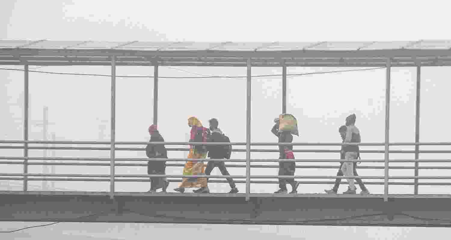 Commuters walk across a foot over bridge on a smoggy winter morning, in New Delhi. Commuters walk across a foot over bridge on a smoggy winter morning, in New Delhi.
