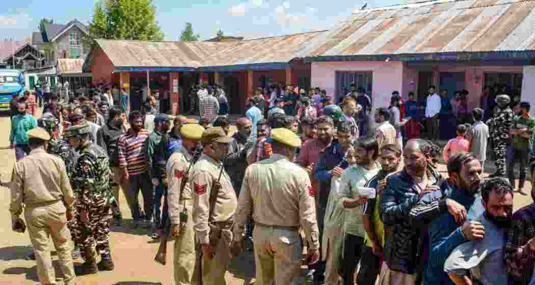 Security personnel stand guard as voters wait in long queues at a polling booth during the 5th phase of elections, in Baramulla district of north Kashmir, Monday, May 20, 2024. Security personnel stand guard as voters wait in long queues at a polling booth during the 5th phase of elections, in Baramulla district of north Kashmir, Monday, May 20, 2024.
