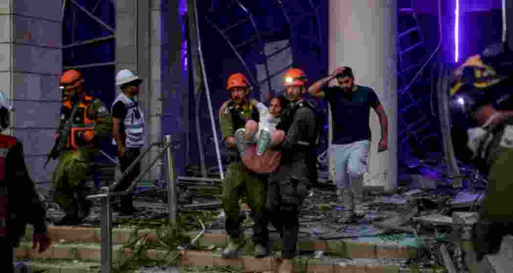 A rescue team carries a woman to safety after missile strikes hit central Israel, as emergency services scramble to respond to the escalating conflict between Iran and Israel. A rescue team carries a woman to safety after missile strikes hit central Israel, as emergency services scramble to respond to the escalating conflict between Iran and Israel.