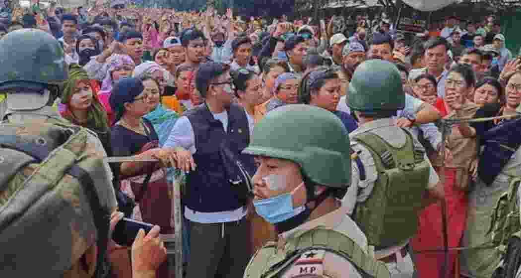 Protesters gather as security personnel block their way along a street during a curfew in Imphal on September 10, 2024. Protesters gather as security personnel block their way along a street during a curfew in Imphal on September 10, 2024.