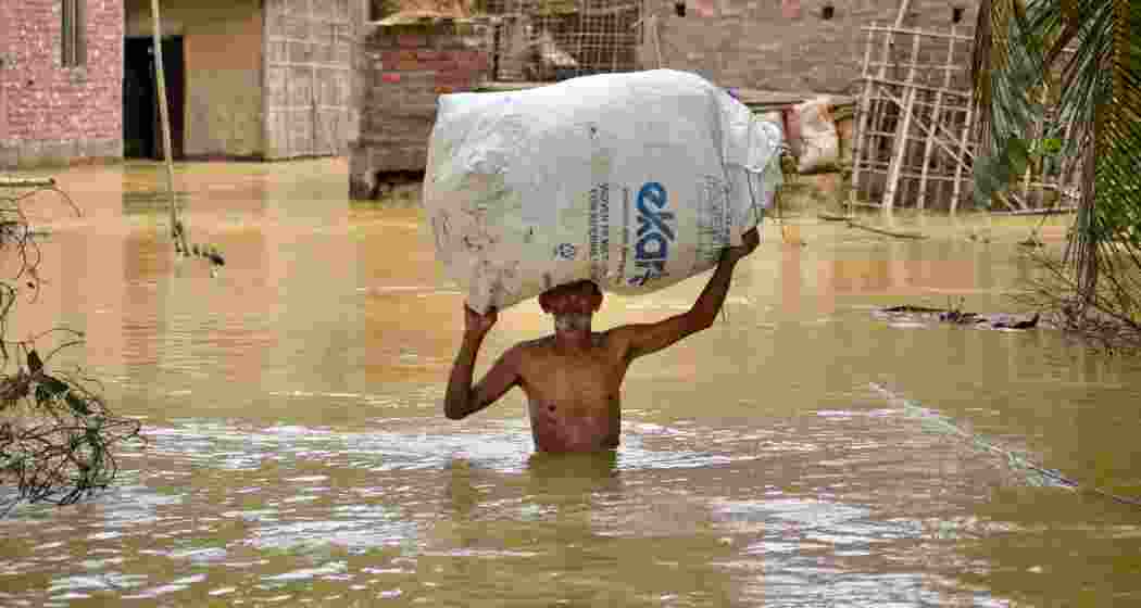 A man carries his belongings as he walks through a flooded road following rains after the landfall of cyclone 'Remal', in Nagaon district of Assam on Saturday. A man carries his belongings as he walks through a flooded road following rains after the landfall of cyclone 'Remal', in Nagaon district of Assam on Saturday.