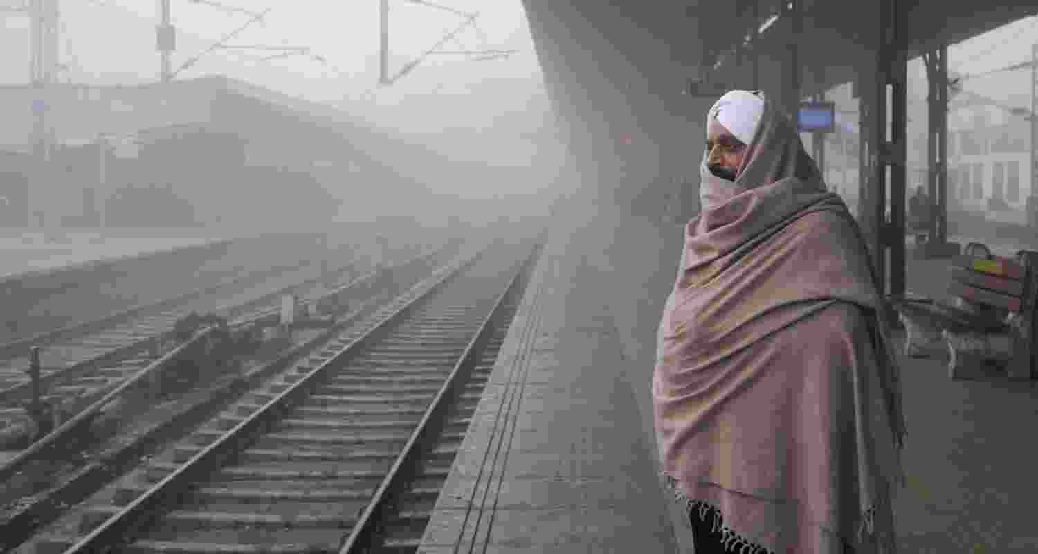 A commuter waits for a train at a railway station amid dense fog during a cold winter morning, in Amritsar.  A commuter waits for a train at a railway station amid dense fog during a cold winter morning, in Amritsar.