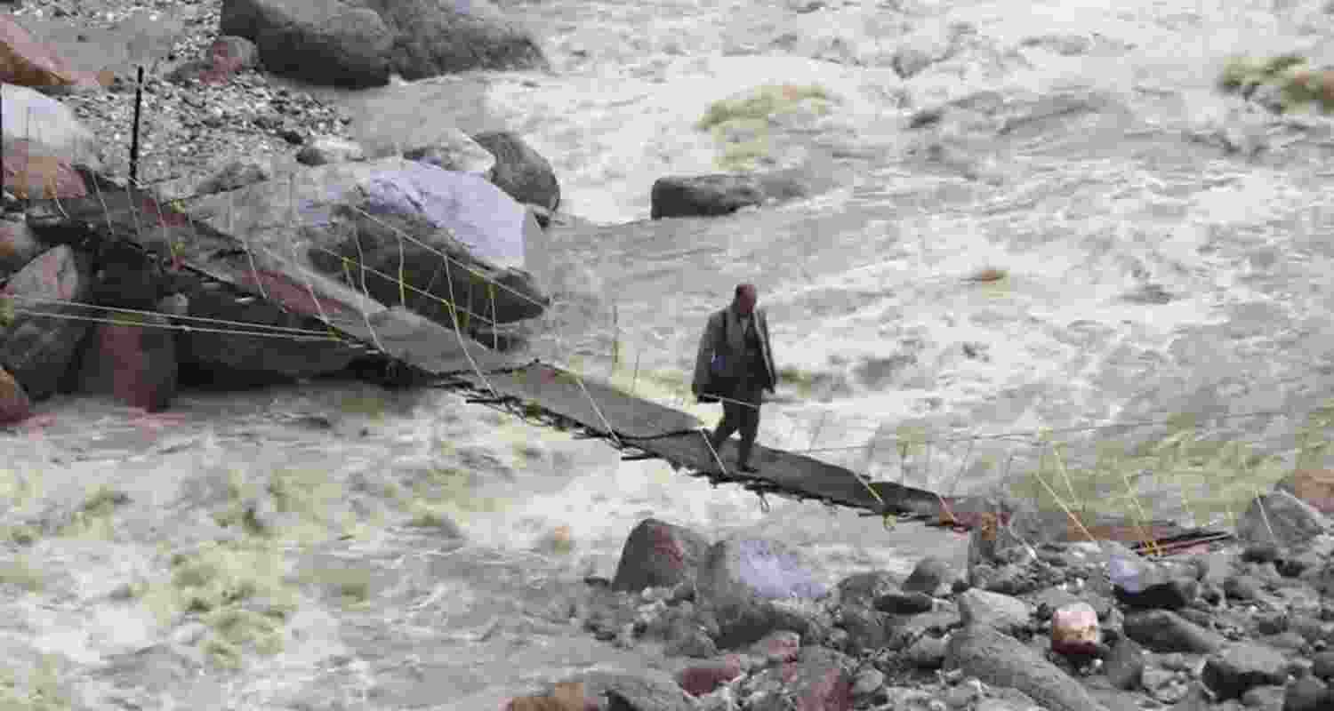 A man crosses a bridge at an affected site following cloudburst at Samej village, in the Rampur area of Shimla. A man crosses a bridge at an affected site following cloudburst at Samej village, in the Rampur area of Shimla.