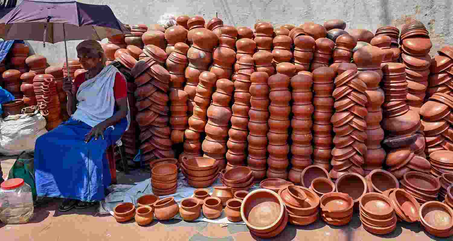 Clay pot vendor patiently awaits customers before Attukal Pongala, a 10-day religious festival at Attukal Bhagavathy Temple, Thiruvananthapuram, Kerala, India." Clay pot vendor patiently awaits customers before Attukal Pongala, a 10-day religious festival at Attukal Bhagavathy Temple, Thiruvananthapuram, Kerala, India."