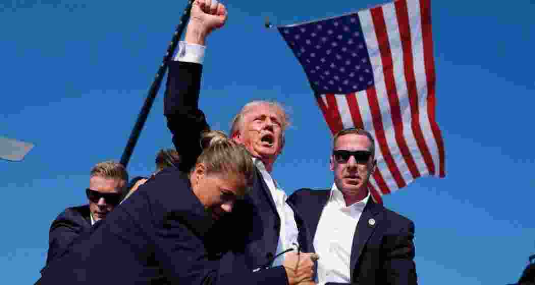 Trump, supported by security personnel, after being grazed by a bullet. Trump, supported by security personnel, after being grazed by a bullet.