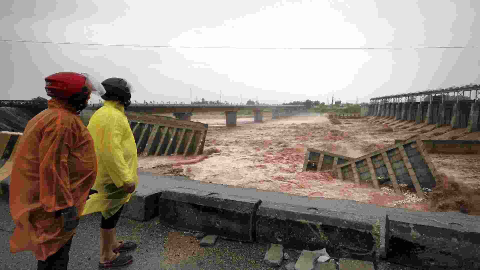 People protect themselves with raincoats while looking at the damaged remains of the 4th Tawi Bridge, after rain continues to lash parts of the city, in Jammu, Wednesday. People protect themselves with raincoats while looking at the damaged remains of the 4th Tawi Bridge, after rain continues to lash parts of the city, in Jammu, Wednesday.